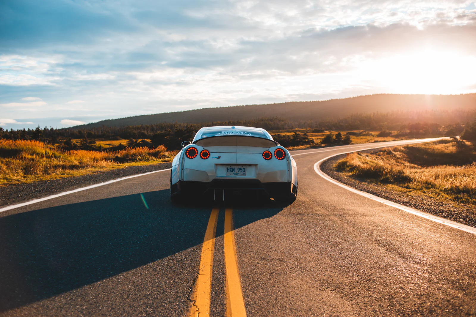 A car driving down an open road at sunset
